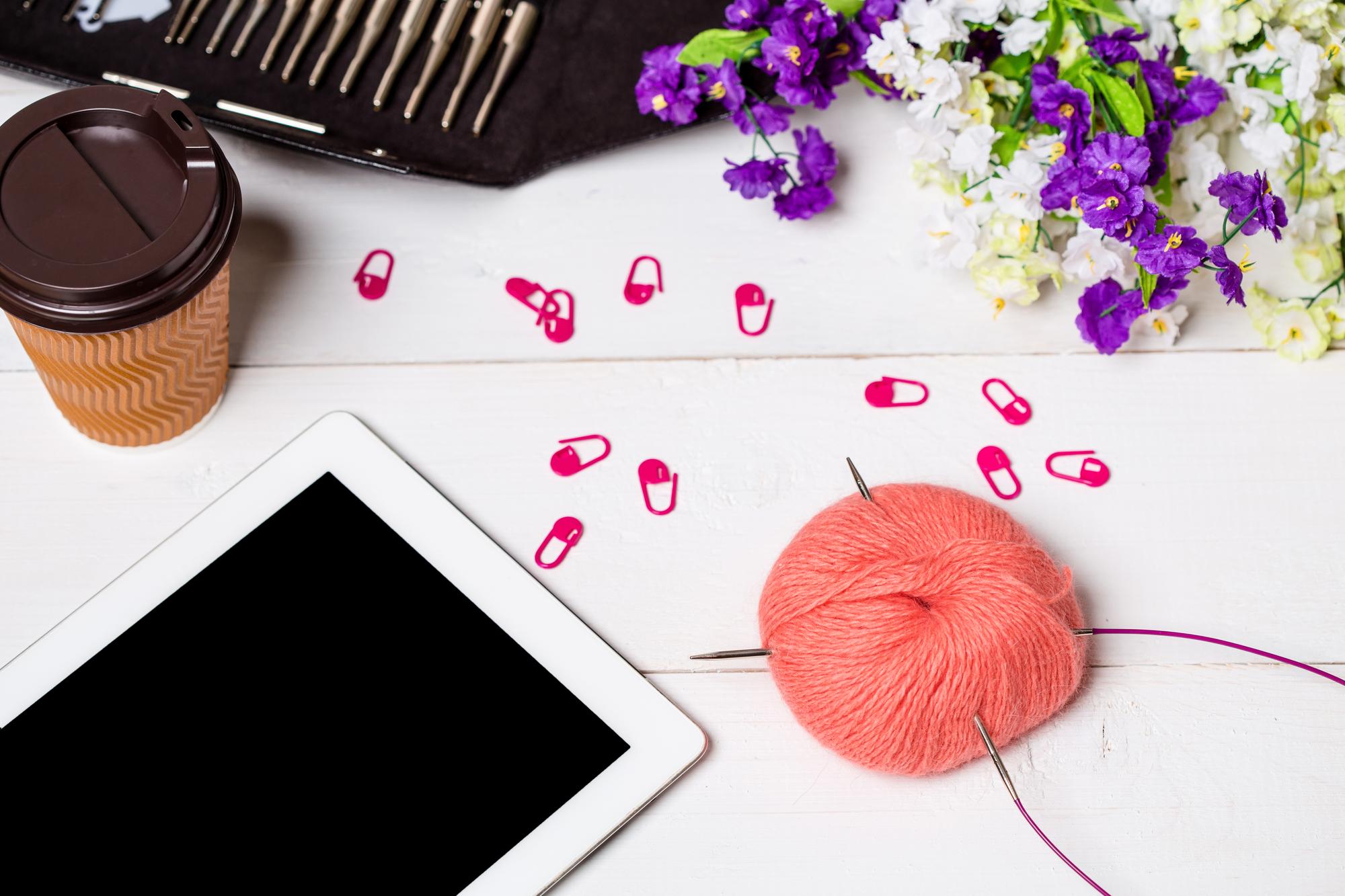studio table with threads, hoop and a laptop showing a vector embroidery design